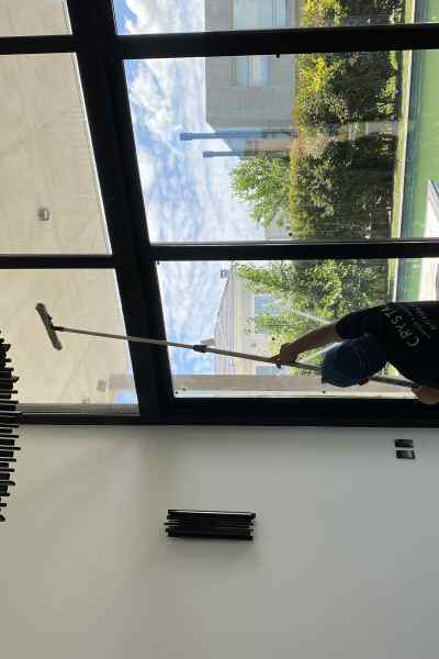 Una operaria limpiando un ventanal. Plan mantenimiento y tratamiento de vidrios